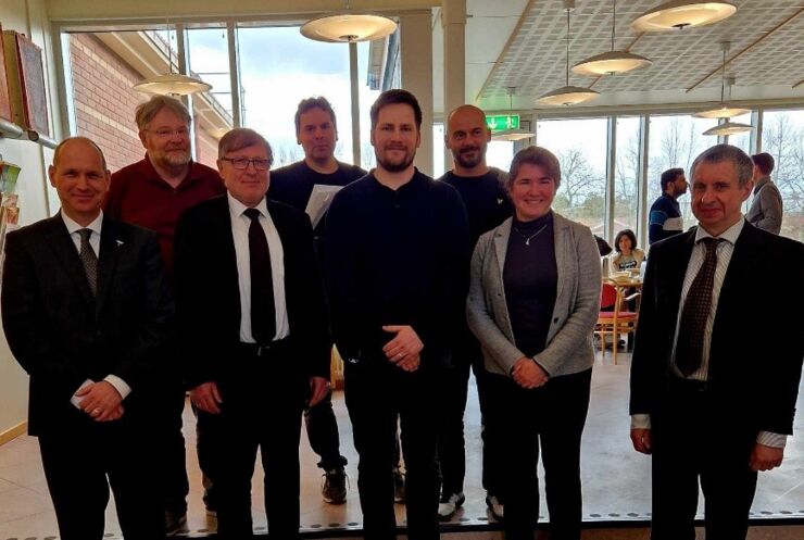 researchers, men and women, stand in two rows and smile to the camera